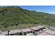 Angle aerial view of houses at the foot of a hill covered with lush grass and shrubs against a clear, blue sky at 6945 N Fargo Trl, Littleton, CO 80125