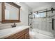 Updated bathroom features a wood-framed mirror, vanity, and stylish glass enclosed tub/shower at 8092 Ponderosa Ln, Parker, CO 80138