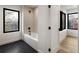 A modern bathroom with a shower and soaking tub along with black hardware and black trimmed window at 4303 Osceola St, Denver, CO 80212