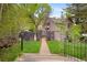 Charming front yard featuring a brick walkway, lush lawn, mature trees and decorative fencing at 715 Main St, Georgetown, CO 80444