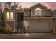 The front of the home showcases a two-car garage with beige siding, mountain views, and a stairway to the entrance at 28110 Meadow Dr, Evergreen, CO 80439