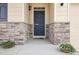 Inviting front entryway with stone accents, a dark blue front door, and seasonal floral planters at 2122 Opal Ave, Brighton, CO 80603