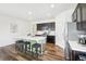 Bright kitchen boasts an island with seating, stainless appliances, and dark wood floors at 2122 Opal Ave, Brighton, CO 80603