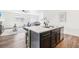 Open concept kitchen with dark cabinets, a marble island, and a view to the living and dining rooms at 2122 Opal Ave, Brighton, CO 80603