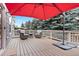 Relaxing outdoor wooden deck with cushioned chairs, a small table, and a large red umbrella at 1668 Rosemary Dr, Castle Rock, CO 80109