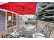 Outdoor wooden deck with a glass-top table, chairs, and a large red umbrella at 1668 Rosemary Dr, Castle Rock, CO 80109