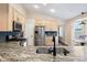 Close-up of a kitchen island with granite countertop, stainless steel appliances, and light wood cabinets at 1668 Rosemary Dr, Castle Rock, CO 80109