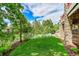Grassy backyard with a lush landscape and stone features on the home's exterior with a deck in the background at 24965 E Roxbury Pl, Aurora, CO 80016