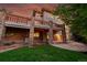 Two-story home featuring a stone patio with stone pillars, manicured lawn, and a lush backdrop of trees at 24965 E Roxbury Pl, Aurora, CO 80016