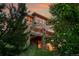 Exterior view of the home featuring a large deck, stone pillars, and surrounded by lush greenery at 24965 E Roxbury Pl, Aurora, CO 80016