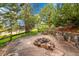 Outdoor fire pit area with stone pavers, surrounded by trees, providing a cozy space for relaxation and entertainment at 24965 E Roxbury Pl, Aurora, CO 80016