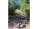 Landscaped backyard with a stone patio, rock retaining wall and fire pit with mature trees surrounding the area at 24965 E Roxbury Pl, Aurora, CO 80016