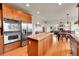 Open kitchen with island and stainless steel appliances leads to living room with fireplace at 24965 E Roxbury Pl, Aurora, CO 80016