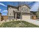 Two-story home showcasing tan siding, stone accents, a two-car garage, and a front yard with a tree and green grass at 25621 E Cedar Pl, Aurora, CO 80018