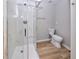 Modern bathroom featuring a glass enclosed shower, toilet and light wood-look floors at 8034 Decatur St, Westminster, CO 80031
