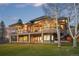 A large two-story home with a sprawling deck, and floor-to-ceiling windows with outdoor lighting at 5602 Silver Bluff Ct, Parker, CO 80134
