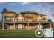 Back view of a home with a stone foundation, large deck with umbrellas, and outdoor lighting at 5602 Silver Bluff Ct, Parker, CO 80134
