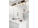 Bright bathroom featuring double sink vanity with framed mirror and modern lighting fixtures at 12715 E 104Th Pl, Commerce City, CO 80022