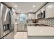 Modern kitchen featuring stainless steel appliances, updated cabinets, backsplash, and quartz countertops at 12685 E Pacific Cir # B, Aurora, CO 80014