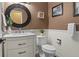 Stylish half bathroom featuring a decorative round mirror, marble countertop, and neutral wall colors at 16158 Whitestone Dr, Parker, CO 80134