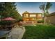 Charming backyard with a stone patio, lush lawn, wooden deck, mature trees and lovely exterior lighting at 4307 Lily Gulch Trl, Castle Rock, CO 80109