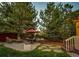 Relaxing backyard patio area with mature trees, a cozy seating area, and access to a wooden deck at 4307 Lily Gulch Trl, Castle Rock, CO 80109