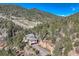 A gorgeous house nestled in a forest, with a driveway leading to the garage, and mountain views beyond at 9659 S Turkey Creek Rd, Morrison, CO 80465