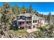 An aerial view showcases a stunning house nestled in a rocky, wooded landscape at 9659 S Turkey Creek Rd, Morrison, CO 80465