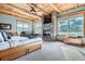 Sun-filled main bedroom with stone fireplace, beamed wood ceiling, and large windows offering scenic views at 9659 S Turkey Creek Rd, Morrison, CO 80465