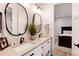 Bathroom with double sinks, granite countertop, oval mirrors, and black hardware, connected to the bedroom at 4711 S Logan St, Englewood, CO 80113