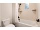 Bathroom featuring a white toilet, white bathtub with shower and shower curtain, and cream-colored tiled walls at 4711 S Logan St, Englewood, CO 80113