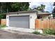 A detached one-car garage with a gray door and white siding is visible behind a wooden fence at 4711 S Logan St, Englewood, CO 80113