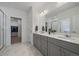 Bright bathroom with double sink vanity, modern fixtures, and a door leading to a walk-in closet at 18001 Herrera Dr, Parker, CO 80134