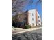 Exterior view of a two-story condo with gray siding and brick accents on a sunny day with mature trees surrounding it at 10785 W 63Rd Pl # 105, Arvada, CO 80004