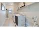 Bright laundry room with tile floor, white shelving, a front load washer and dryer, and an ironing board at 10723 Sedalia St, Commerce City, CO 80022