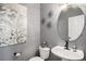 Stylish powder room featuring modern fixtures, decorative mirror, and unique wall art at 13087 Krameria St, Thornton, CO 80602