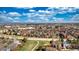 Stunning aerial view of a residential neighborhood with lush greenery and distant cityscape under a vibrant, cloudy sky at 9767 Burberry Way, Highlands Ranch, CO 80129