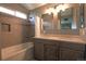 Bright bathroom with double vanity, tiled shower and tub combo featuring a decorative tile accent at 9767 Burberry Way, Highlands Ranch, CO 80129