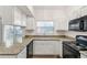 Bright kitchen featuring granite countertops, white cabinetry, and black appliances, complemented by natural light at 10663 Dexter Dr, Thornton, CO 80233