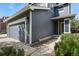 A close-up of a two-story house with blue siding, a gray garage door and landscaping at 5453 S Quatar Ct, Aurora, CO 80015