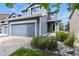 Two-story home with blue siding, a gray garage door, and river rock landscaping in front at 5453 S Quatar Ct, Aurora, CO 80015