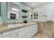 Bright bathroom boasts double sinks with a white vanity, marble countertops, and decoratively placed shelves with towels at 5666 S Havana Ct, Englewood, CO 80111
