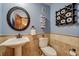 Stylish powder room with stone walls, pedestal sink, toilet and decorative accessories at 5666 S Havana Ct, Englewood, CO 80111