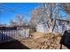 View of the backyard with a white picket fence, shed, and a large tree providing shade at 1193 S Umatilla St, Denver, CO 80223