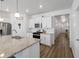 Open-concept kitchen with white cabinetry, granite countertops, stainless steel appliances and hardwood floors at 13408 Wabash St, Thornton, CO 80602