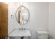 Stylish powder room featuring modern fixtures, a marble vanity top, and an oval mirror with a crystal light fixture at 2025 Ash St, Denver, CO 80207