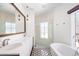 Modern bathroom features double sinks, sleek vanity, glass shower, and standalone tub with black-and-white patterned tile at 2025 Ash St, Denver, CO 80207