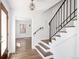 Inviting entryway features hardwood floors, elegant staircase with black wrought iron railing, and charming chandelier at 2025 Ash St, Denver, CO 80207