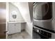 Bright laundry room with stacked washer and dryer, countertop, cabinet storage, and unique round window at 2025 Ash St, Denver, CO 80207