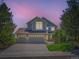 Charming two-story home with a three-car garage, manicured lawn, and mature trees set against a stunning evening sky at 1674 Bent Grass Cir, Castle Rock, CO 80109